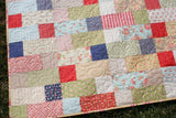 Layer cake-friendly quilt pattern, Stepping Stones, shown as a modern baby quilt by Kristin Blandford Designs, ideal for quick, easy sewing.