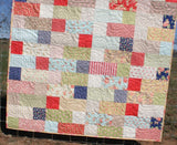 Stepping Stones pattern by Kristin Blandford Designs – a beginner-friendly baby and throw quilt pattern using 10" layer cakes and bold fabrics.