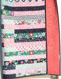 Jelly roll quilt pattern – Striped Out digital PDF by Kristin Blandford Designs, displayed as a finished lap throw with curved quilting and polka dot binding.