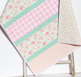 Easy modern quilt pattern featuring diagonal strip piecing and coordinated fabrics displayed in a clean contemporary baby quilt design.