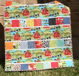 Beginner-friendly farm quilt pattern with novelty barnyard fabrics, farm animals, and colorful patchwork charm squares for baby quilts.