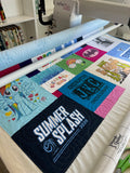 Custom t-shirt quilt in progress on a long arm quilting machine, featuring colorful shirt blocks with logo amd characters