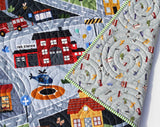Nursery quilt featuring roadway design, cars, helicopters, and buildings, perfect for imaginative floor play or tummy time.