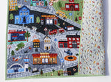 Personalized city scene baby blanket with roadways, buildings, & transport vehicles, handcrafted with quilted cotton layers.