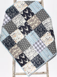 Baby quilt kit with woodland deer, owls, and teepee fabrics in navy and gray rustic patchwork design.