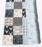 Custom woodland patchwork quilt for newborns, featuring soft fabrics, forest prints, and personalized name stitching.