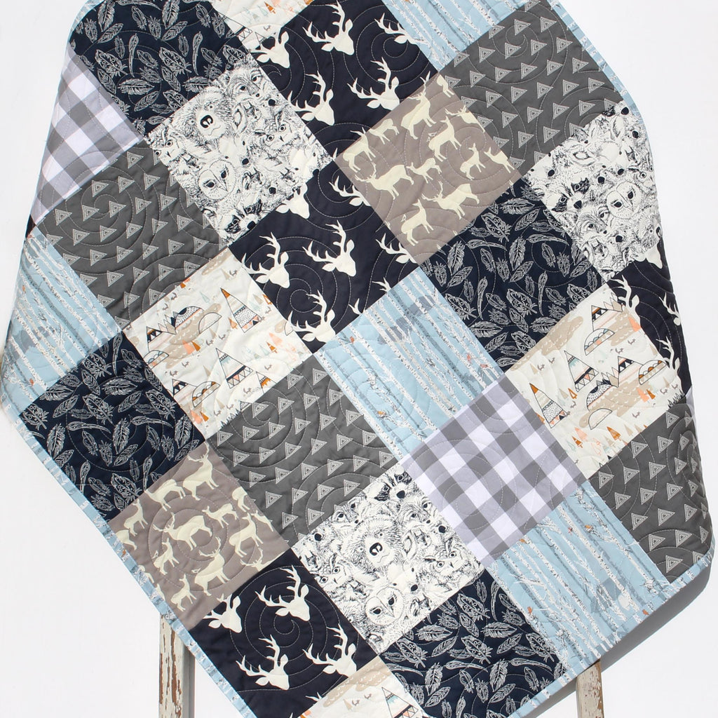 Handmade woodland patchwork quilt with embroidered name, featuring forest animals, deer, trees, and soft neutral fabrics.