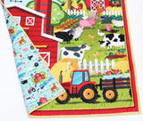 Nursery quilt panel featuring barns and farm animals, yellow stripe binding, your choice of farm‐scene backing fabric included.