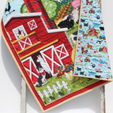 Farm animal baby blanket kit with barn centerpiece, bright binding, and choices for tractor or pastoral backing fabric.