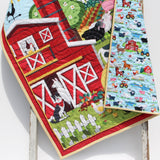 Custom-embroidered baby blanket featuring barn scene and smiling farm animals, ideal for nursery décor or baby shower gift.
