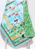 Personalized baby quilt with bright construction vehicle prints and embroidered name, handmade for nursery décor.