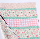 cottage style handmade quilt with pastel floral cotton fabrics and diagonal stripe layout